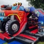 A 3D Monster Truck style bouncy castle with slide side view