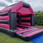 An Adult Pink & Black velcro style bouncy castle side view